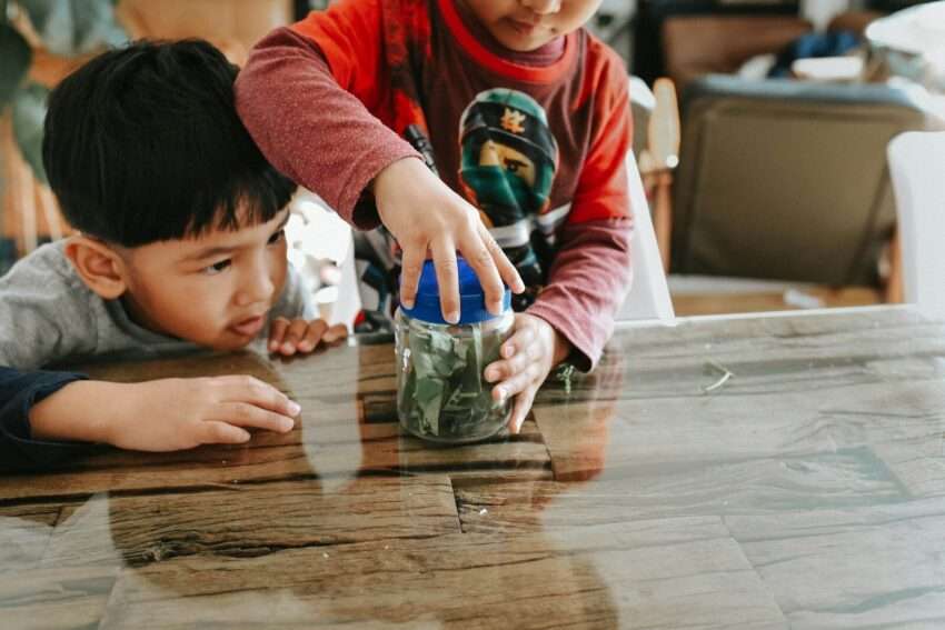 two children are playing with a jar of money